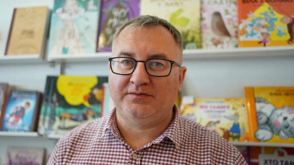 Andrej Januškevič in front of a shelves of books