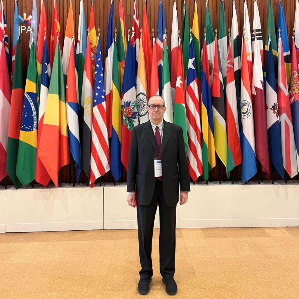 Givanni Hoepli in front of a wall of flags.