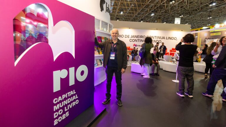 SNEL President Dante Cid at the Biennal de Rio next to a sign showing Rio World Book Capital City